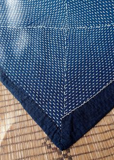 a blue and white table cloth on top of a bamboo mat with an umbrella in the background