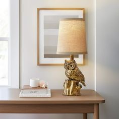 an owl lamp sitting on top of a table next to a coffee cup and book