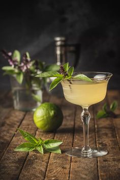 a glass filled with lemonade and garnish next to limes on a wooden table