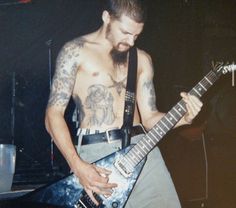 a shirtless man playing an electric guitar