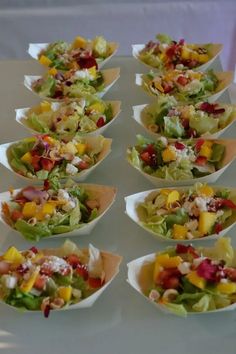 many different types of salads in small bowls on a white tableclothed surface