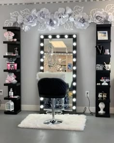 a room with a chair, mirror and lights on the wall above it that is decorated in white flowers