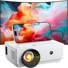 a white projector sitting on top of a table next to a large screen tv