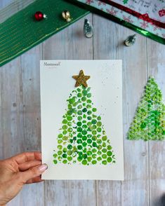 someone is holding up a christmas card with a tree made out of circles and stars