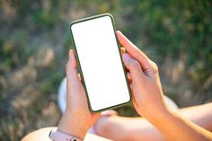 a person holding up a smart phone in their hands with a blank screen on it