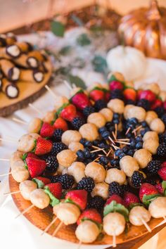 a cake decorated with fruits and skewers on top of a wooden table next to other desserts