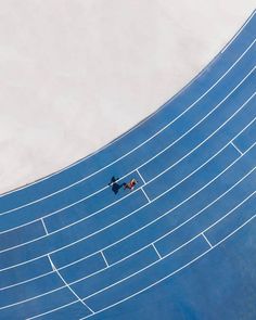 two people are running on a blue track