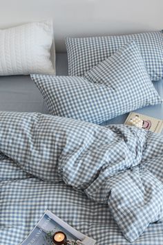 a blue and white checkered comforter on top of a bed next to pillows