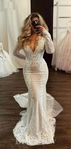 a woman taking a selfie in a wedding dress with long sleeves and open back