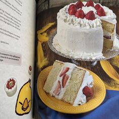 an open book with two slices of cake and strawberries on the plate next to it