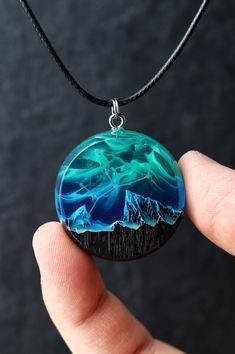 Handmade round pendant from black hornbeam wood and resin with zodiac constellation and mountains inside.  Each piece of this handmade jewelry is a unique expression of art, making it a perfect personalized gift for anyone special. Glow in the dark! D E T A I L S : * Made to order epoxy resin necklace * Materials: black hornbeam wood (impregnated with protective eco oils) and epoxy resin * Shipped in a box for easy gift giving * Each piece is handmade. The wood we use is of high quality and abso Resin Wood Jewelry, Wood And Resin Jewelry, Epoxy Resin Necklace, Wood And Resin Pendants, Nature-inspired Round Resin Pendant Jewelry, Blue Resin Necklaces With Ocean-inspired Style, Nature-inspired Resin Round Pendant Necklaces, Wood Resin Necklace, Wood Resin Jewelry