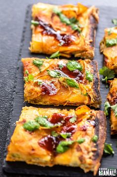 several square pieces of pizza with toppings arranged on a slate board, ready to be eaten