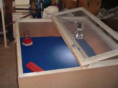 a bird cage sitting on top of a blue mat next to a red container with a beak in it