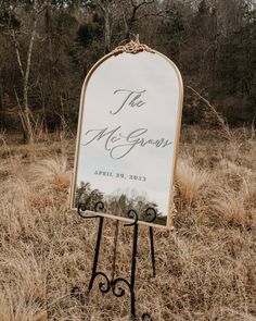 a sign in the middle of a field with trees and grass behind it that says, the mr and mrs