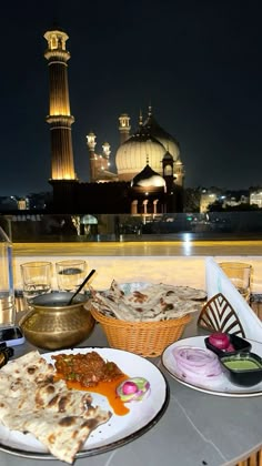 two plates of food sit on a table in front of a view of the city at night