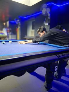 a man leaning over a blue pool table