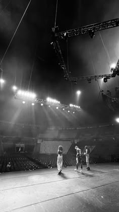 some kids are playing basketball in an empty arena with lights shining on the bleachers