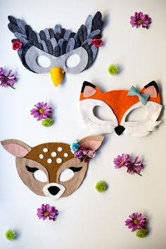 three masks with different designs on them and flowers in the background, one is made out of felt