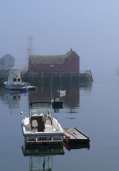 a small boat is docked in the water near some houses and boats on a foggy day