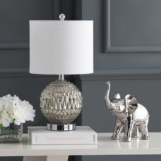 an elephant lamp sitting on top of a table next to a vase with flowers in it