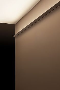 an empty room with a light on the ceiling and a black door in the corner