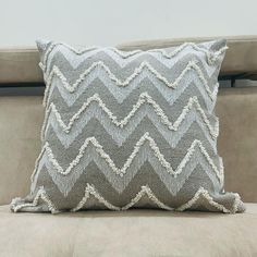 a gray and white pillow sitting on top of a couch