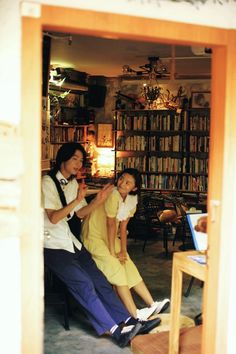 two people sitting on a chair in front of a bookshelf