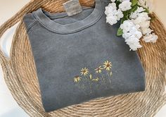 a t - shirt sitting on top of a wicker basket next to white flowers