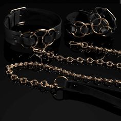 three different types of leather collars and cuffs with chains attached to each other on a black background