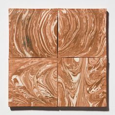 four square pieces of brown marble on a white surface