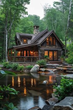 a log cabin is lit up at night in the woods near a stream and rocks