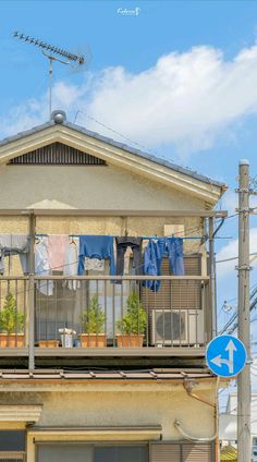 an apartment building with clothes hanging out to dry on the balcony, and a blue street sign in front of it