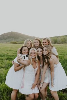 a group of young women standing next to each other on top of a lush green field