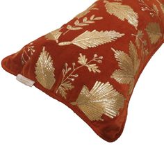 a red pillow with gold leaves on it