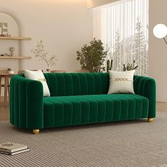 a living room with green velvet couches and white pillows