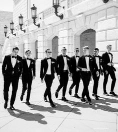 a group of men in tuxedos are walking down the street with sunglasses on