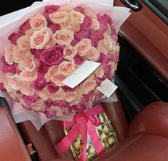 a bouquet of roses and chocolates in the back seat of a car with a pink ribbon tied around it