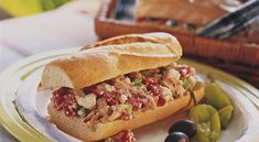 a sandwich on a plate with olives and bread