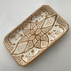 a brown and white decorative ceramic dish on a white tableclothed surface, with an intricate design in the center