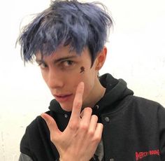 a young man with blue hair making the peace sign