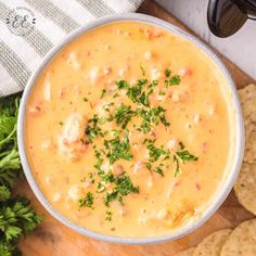 a white bowl filled with soup next to tortilla chips and garnished with parsley