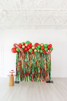 an arrangement of red, green and gold balloons on a white wall with streamers