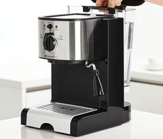 a person is using a coffee maker on a counter