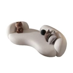 a white couch with two teddy bears sitting on it's back and the pillow is shaped like a recliner