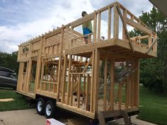 a man standing on the back of a truck with a house built into it's roof