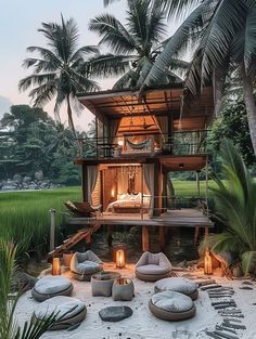 a house that is surrounded by palm trees and lights in the sand at night time