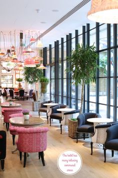 the interior of a restaurant with pink and black chairs, potted plants and chandeliers