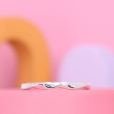 a silver ring sitting on top of a pink surface