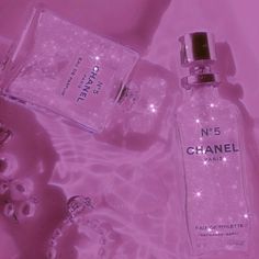 chanel no 5 perfume bottle next to other items on pink background with sparkling lights