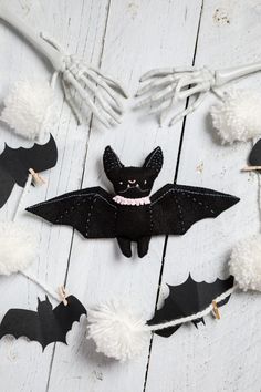 a bat decoration with pom - poms hanging from it's side on a white wooden surface